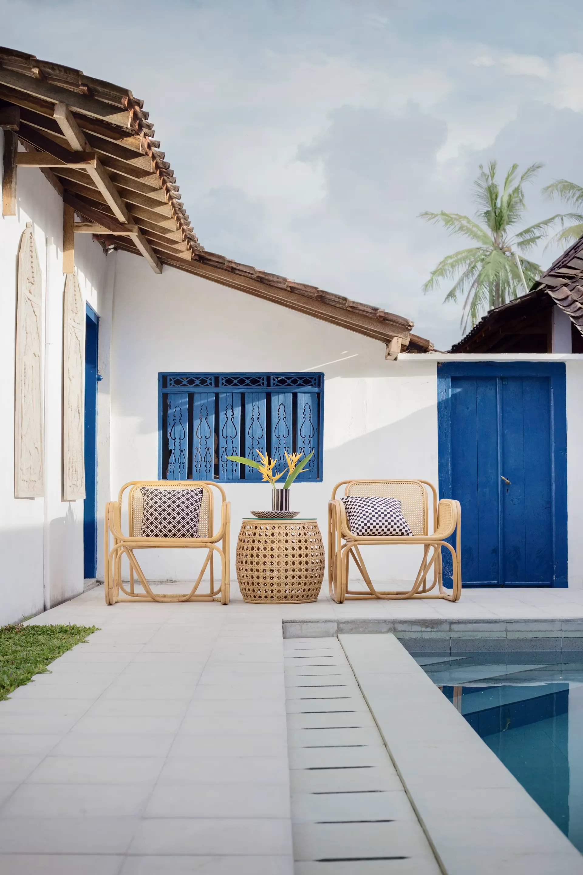 Coastal home with hand-carved blue doorway and rattan lounge chairs